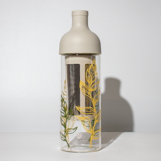 Unsere Eistee Flasche "Clara" aus Glas ist mit gelben und grünen Blättern verziert.