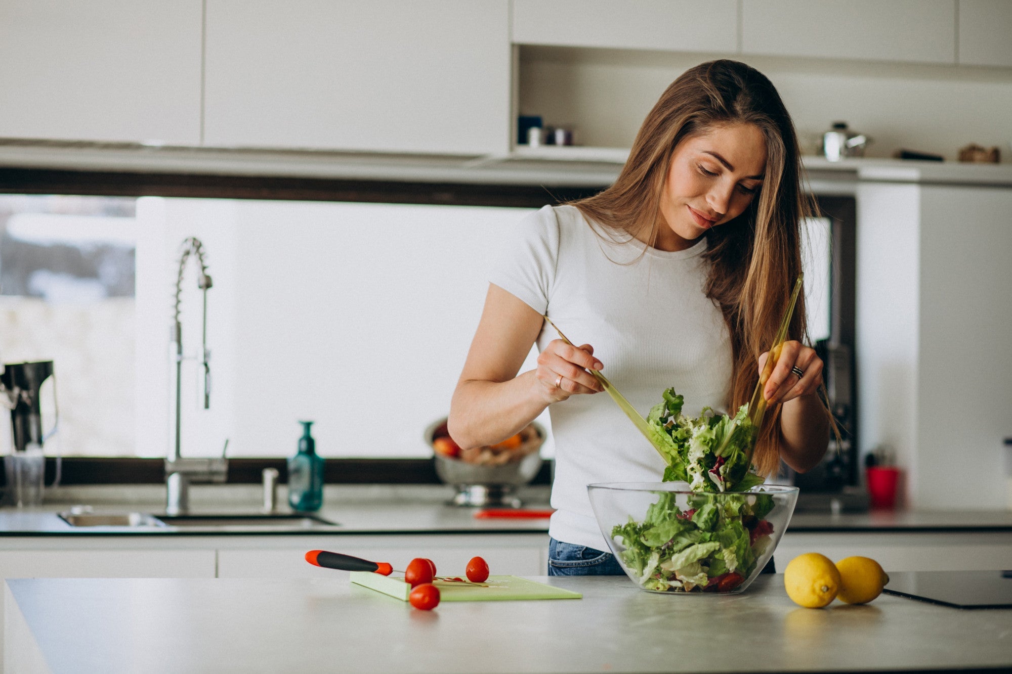 Eine Frau die in ihrer Küche einen Salat zubereitet.